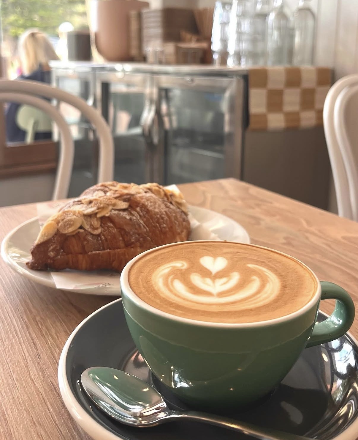 Latte and almond croissant on a timber table