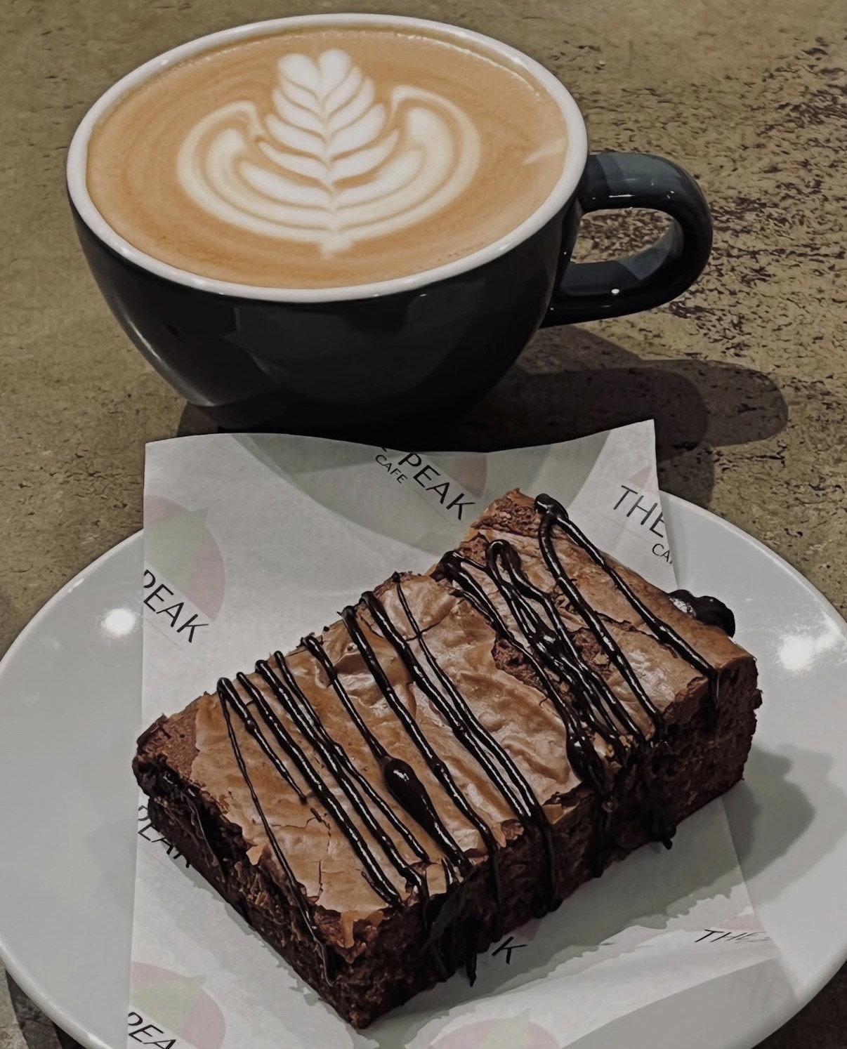 Chocolate brownie with dark chocolate drizzle and a latte