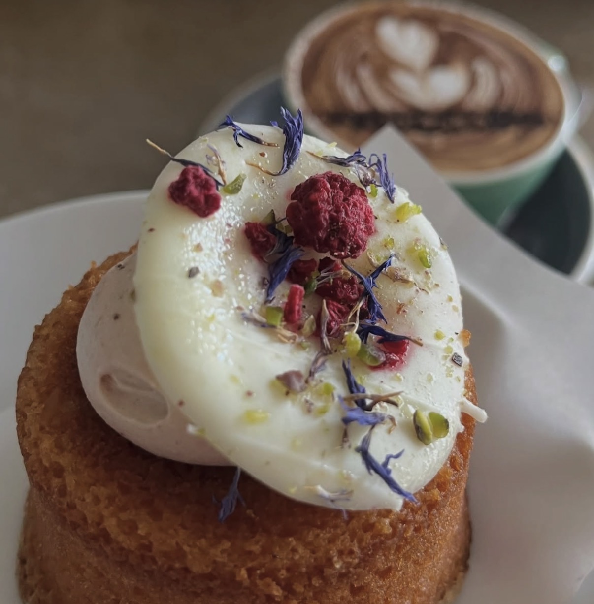 Friand topped with cream, freeze dried raspberry and pistachio
